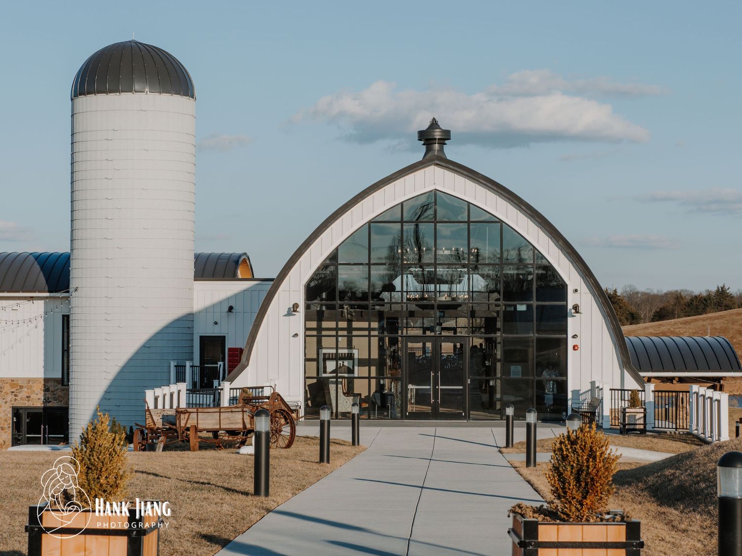 Modern white barn venue with glass facade and silo at Hana Haus, a rustic event space under blue skies.