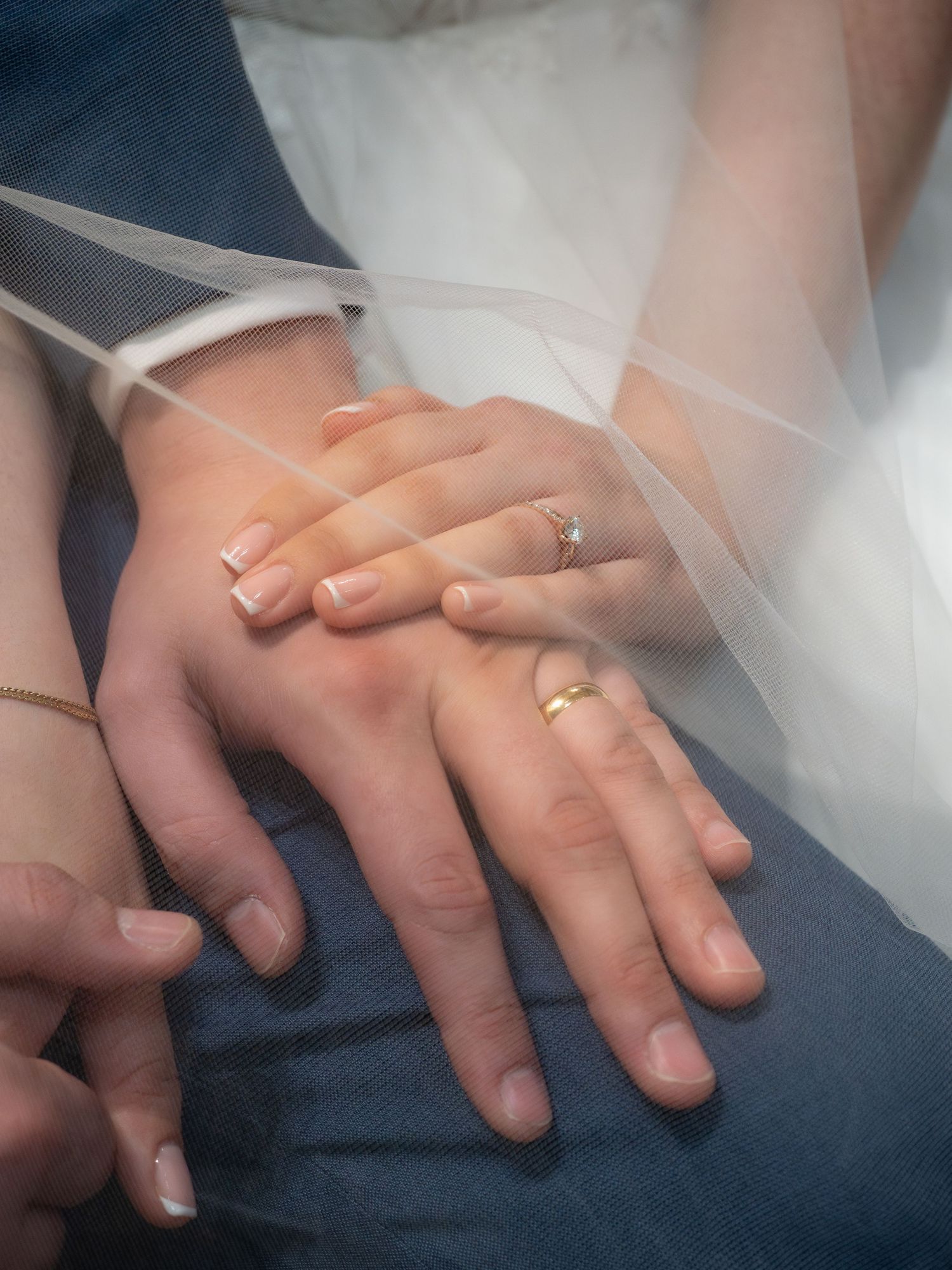 Close-up of newlyweds hands showing wedding rings and engagement ring after Catholic ceremony.