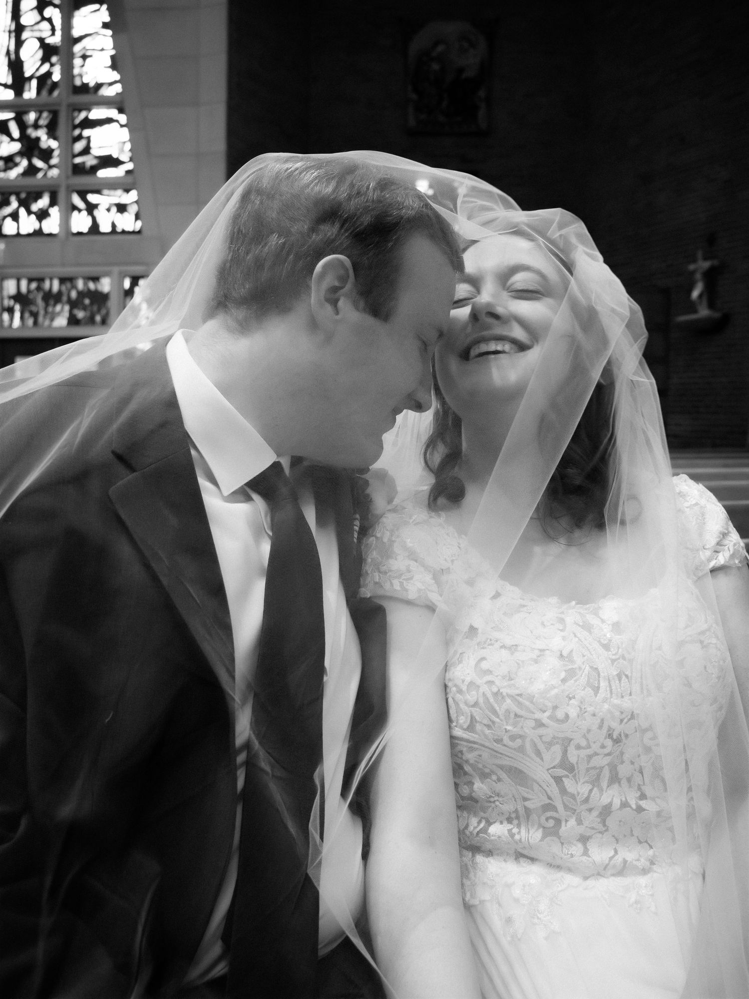 Black and white photo of newlyweds sharing an intimate moment under the bridal veil.