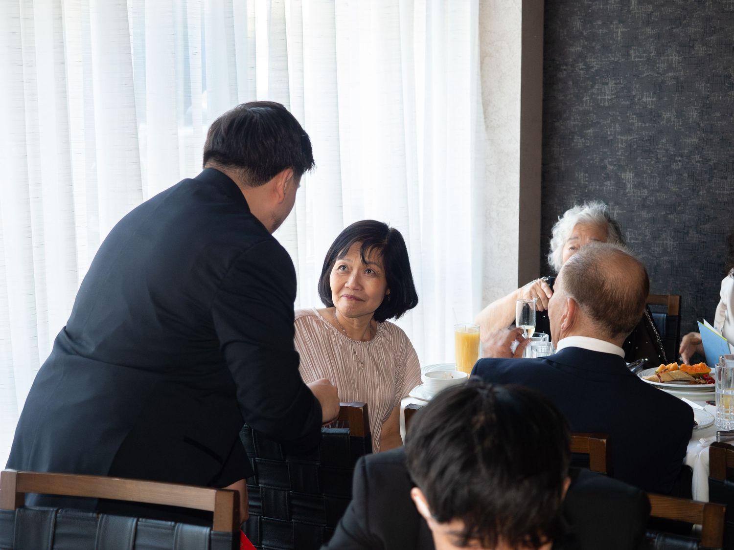 People in formal attire having a conversation at a dining table during a formal event.