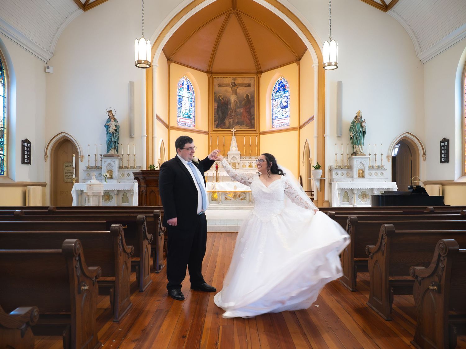 Bride and groom dance joyfully together inside a beautiful Catholic church after their ceremony.