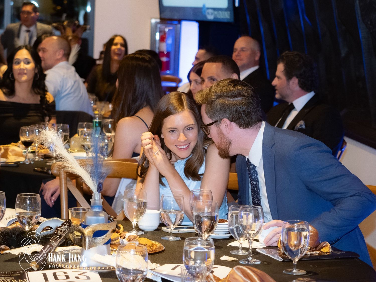 Elegantly dressed guests socializing at a formal gala dinner, smiling and conversing at a decorated banquet table.