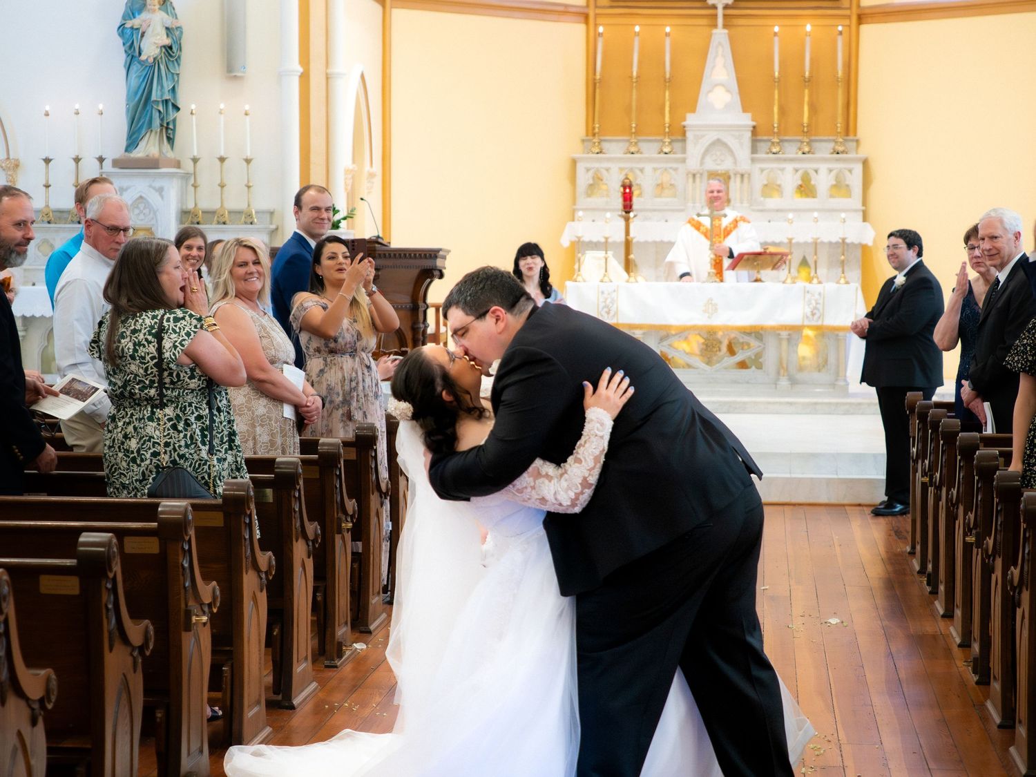 Newlyweds share their first kiss as husband and wife at the church altar before cheering guests.