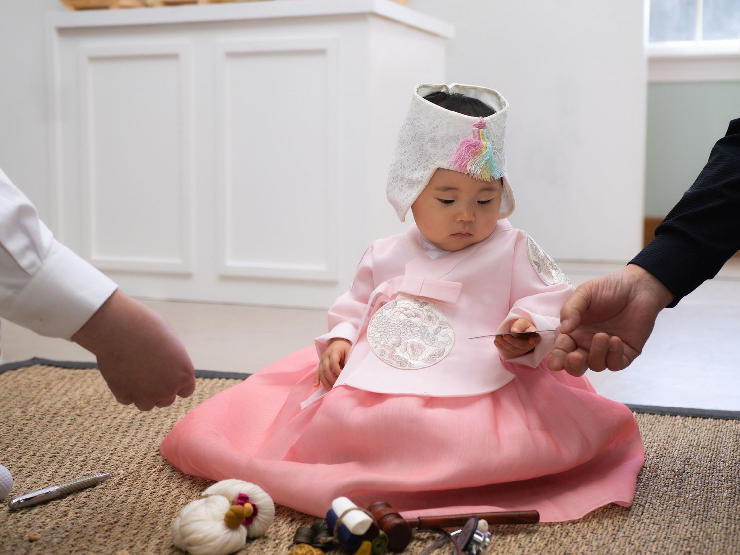 Baby girl in traditional Korean hanbok dress during Dol first birthday celebration ceremony.