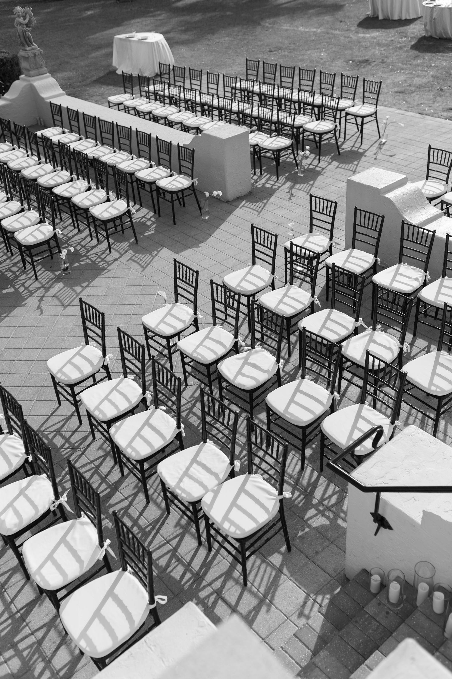 Black and white aerial view of elegant Chiavari chairs arranged in rows for an outdoor wedding ceremony.