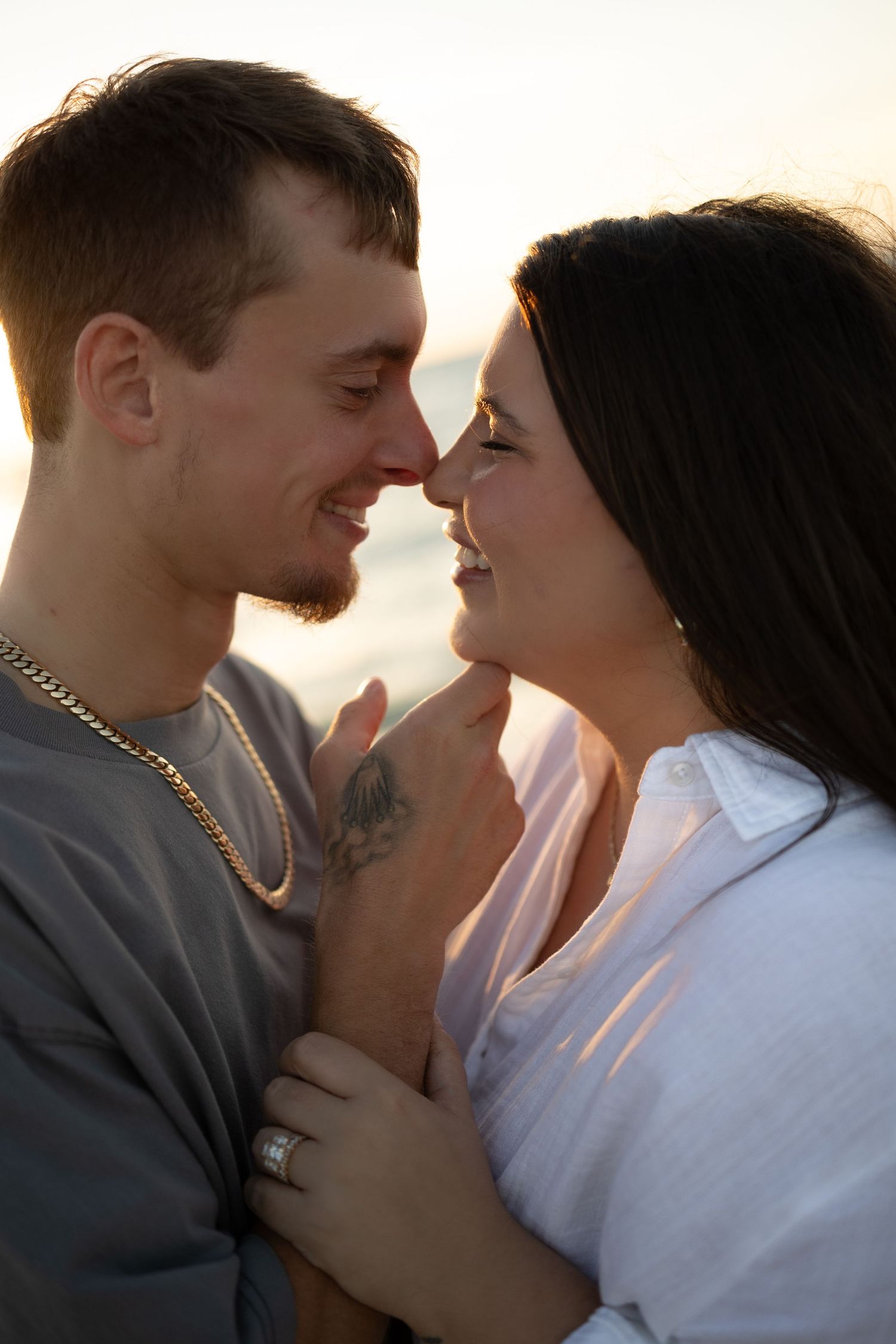 Couple shares a romantic nose-to-nose moment at sunset on the beach.