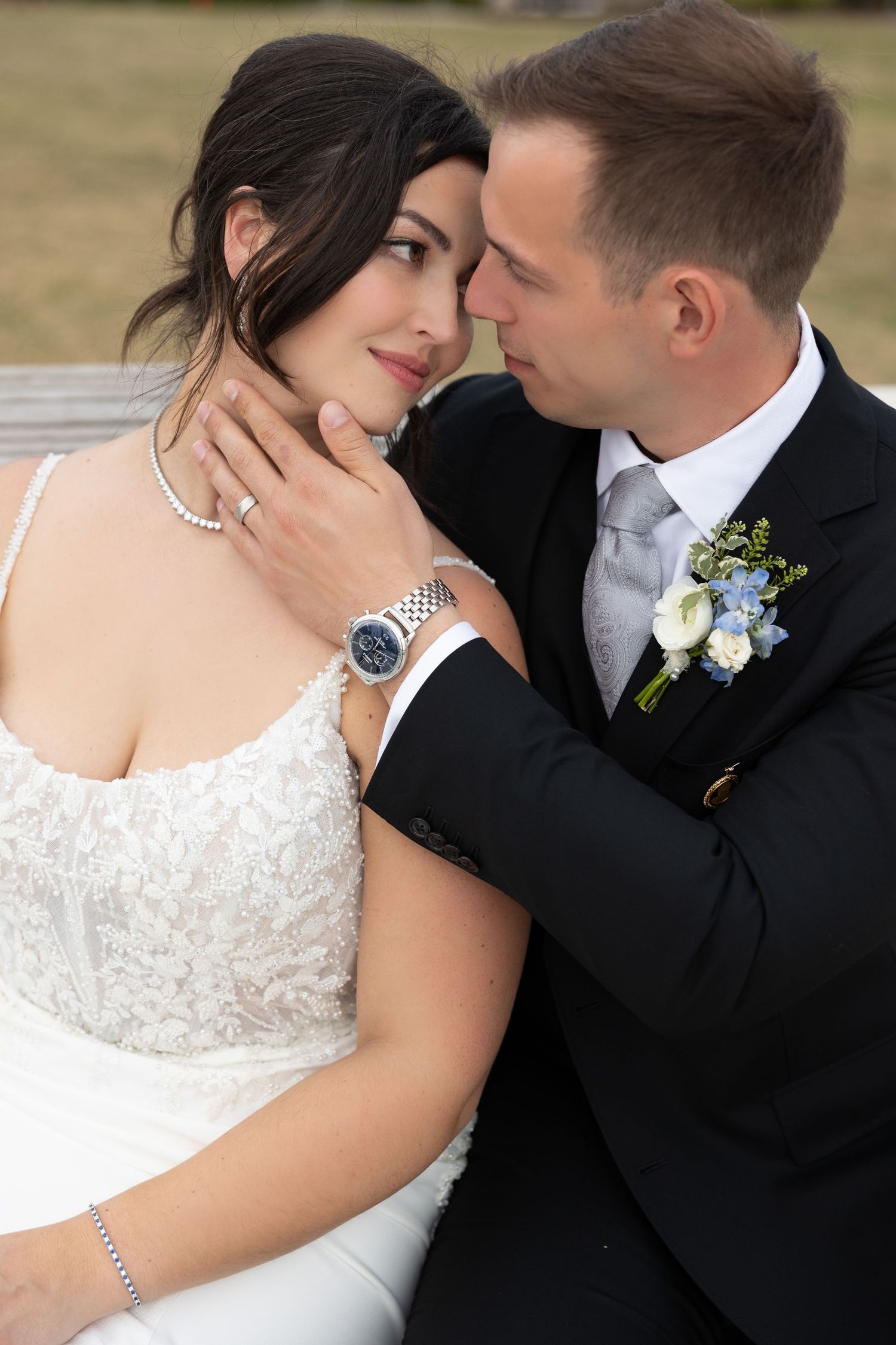 Groom tenderly cups brides face as they share a close romantic moment on wedding day.