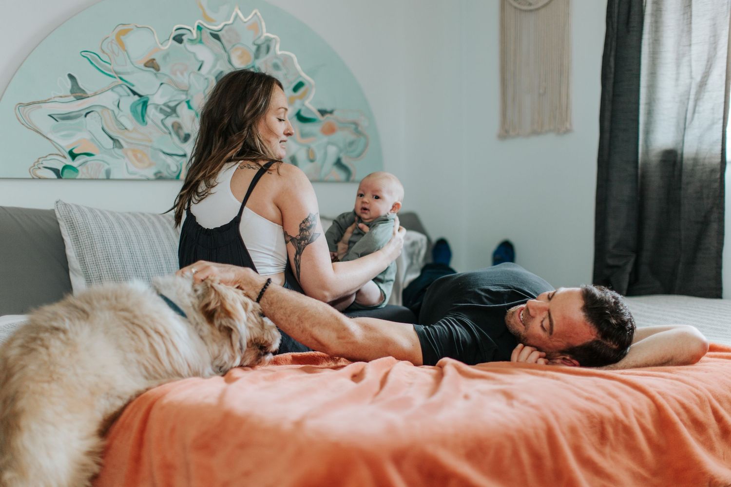 Candid lifestyle photography of family relaxing on coral colored bedding.