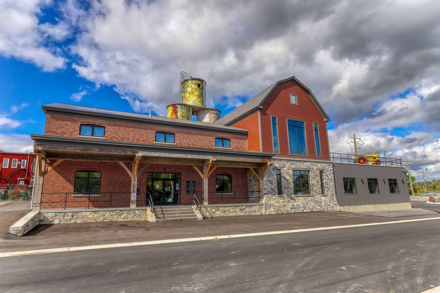 Rustic brick and stone building with large windows under dramatic cloudy sky.