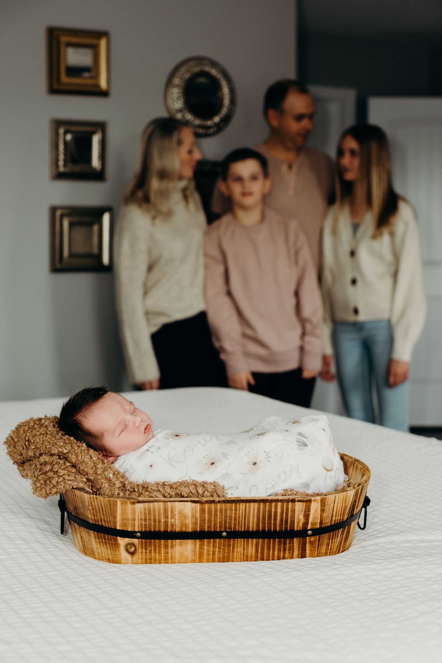 Newborn baby sleeping peacefully in woven basket on white bedding.