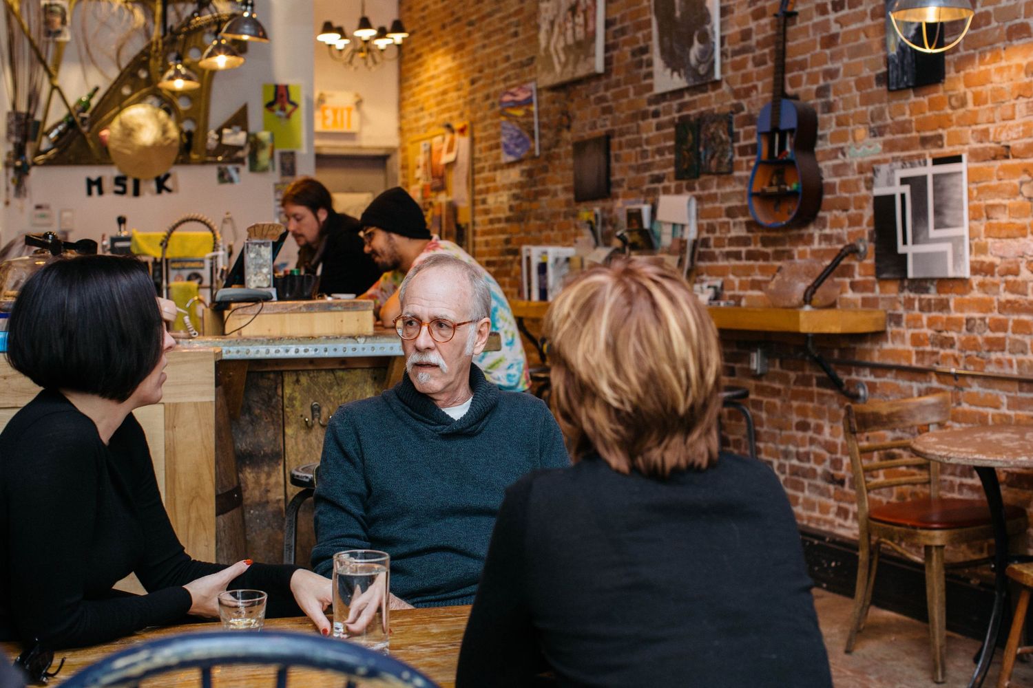 Group meeting in rustic brick-walled restaurant space with warm ambient lighting.