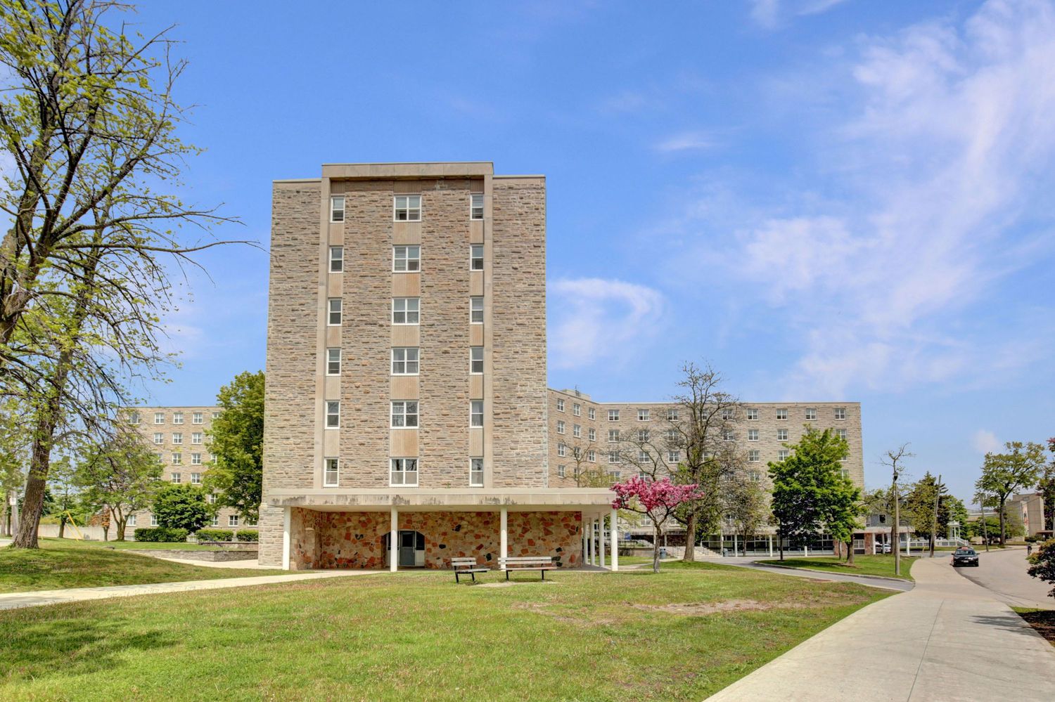 Exterior view of brick apartment building with trees and blue sky.