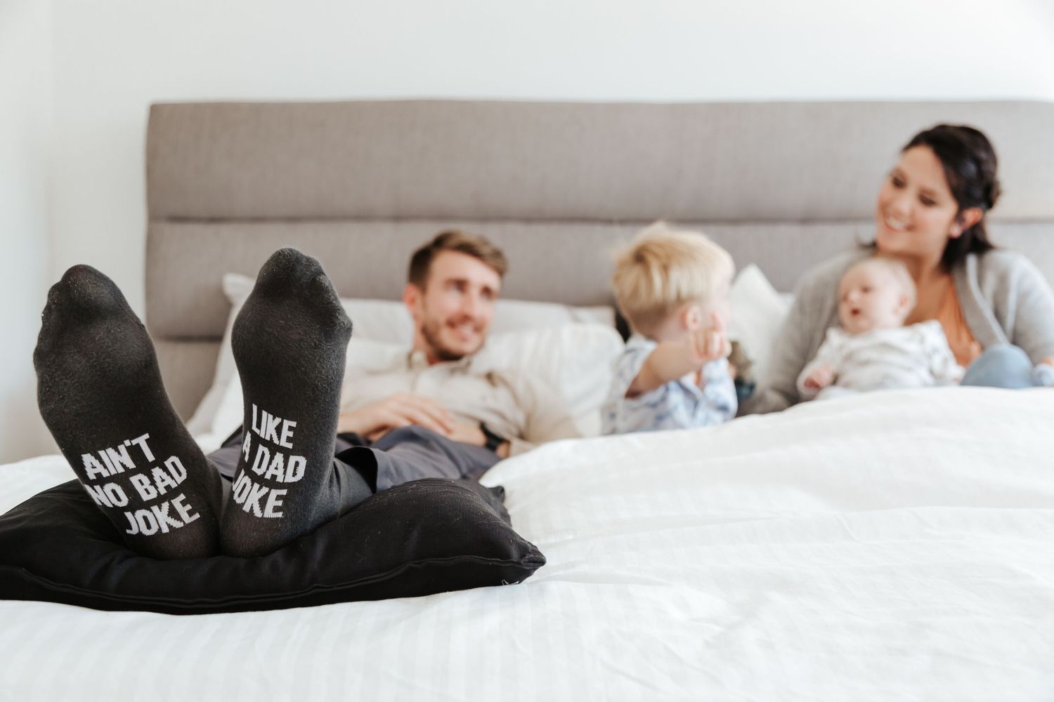 Lifestyle photography session showing a family lying together on a white bed.