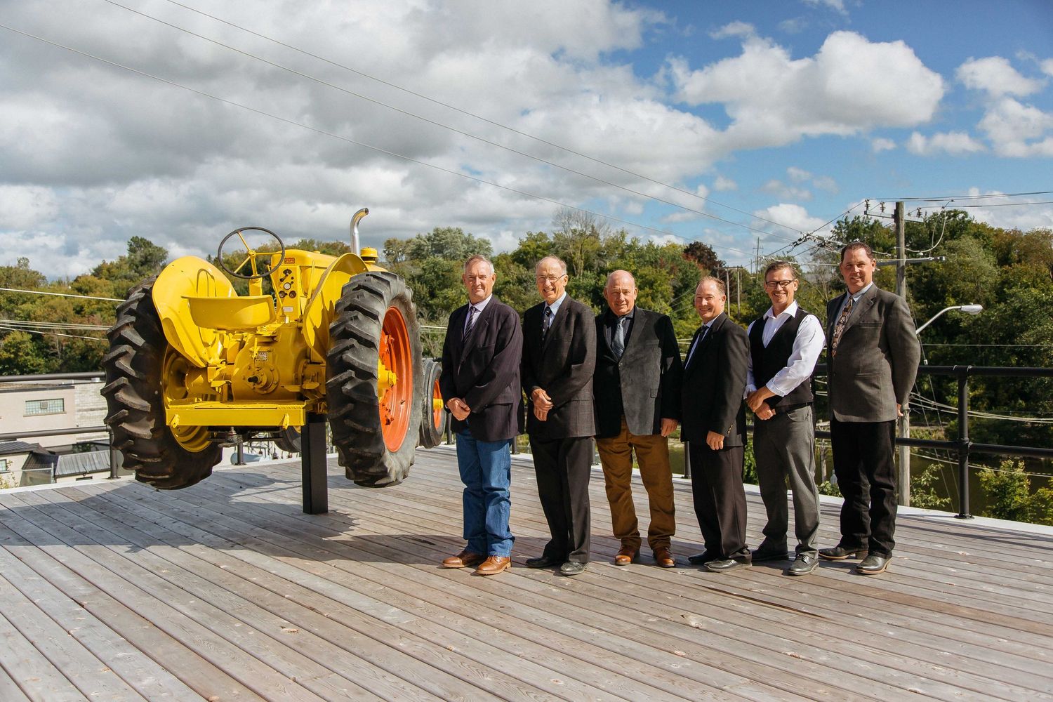 Group of professionals standing outdoors on a deck under blue skies with white clouds.