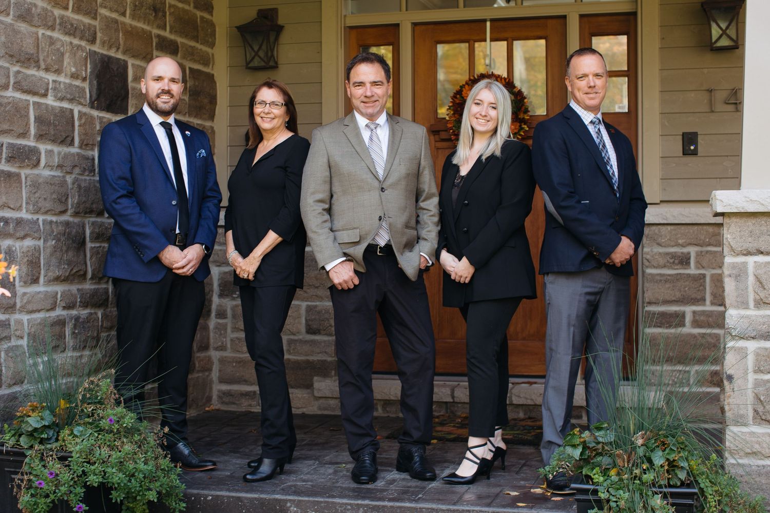 Professional team in business attire poses on stone steps in front of office entrance.
