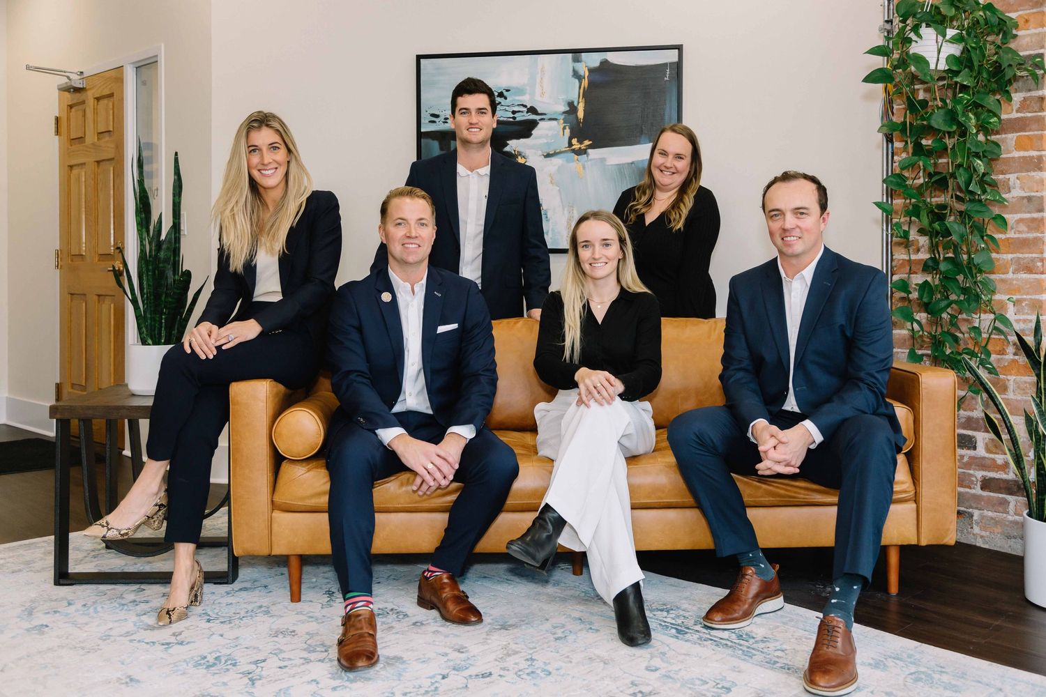 Business team sits together on brown leather couch in modern office space.