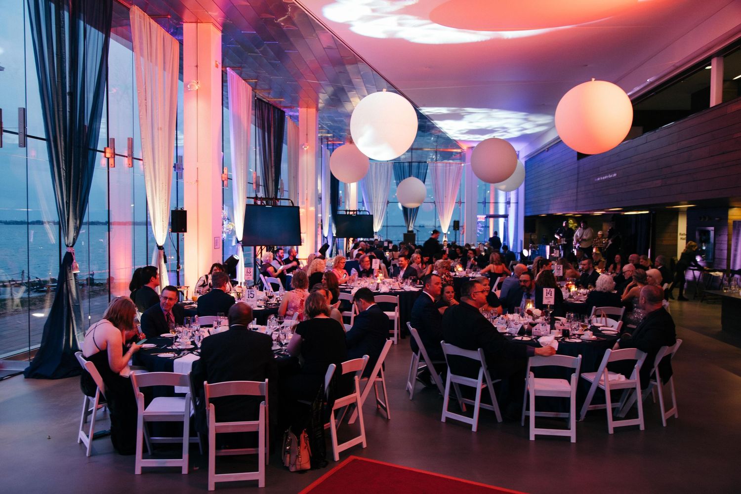 Evening event venue with red ambient lighting and round tables set for dining.