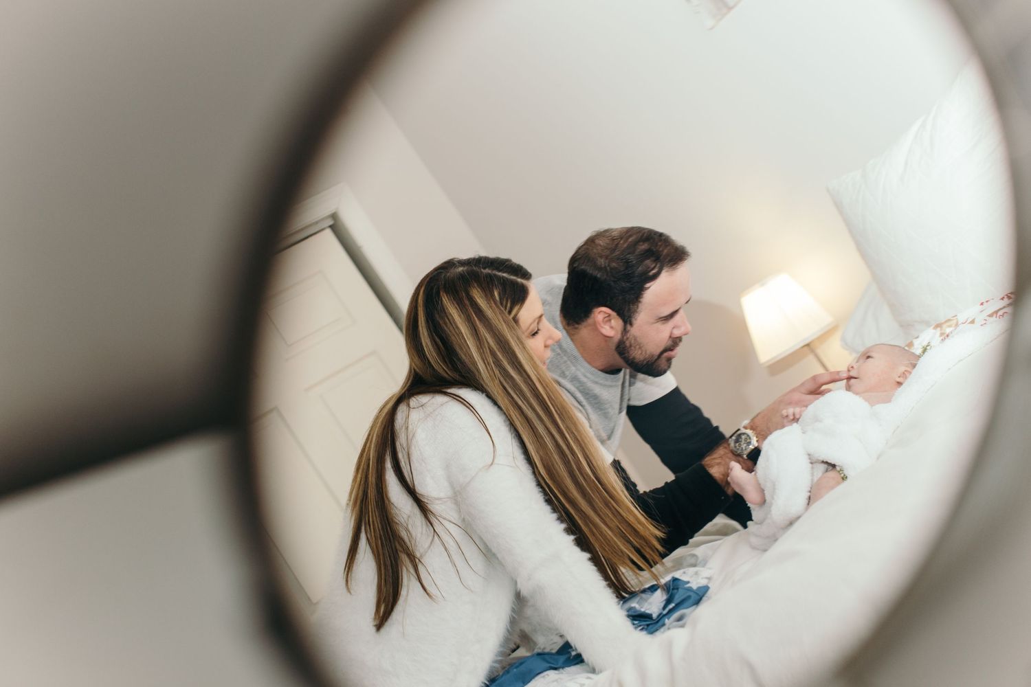 Family wearing matching socks relaxing together on white bedding in a cozy bedroom setting.