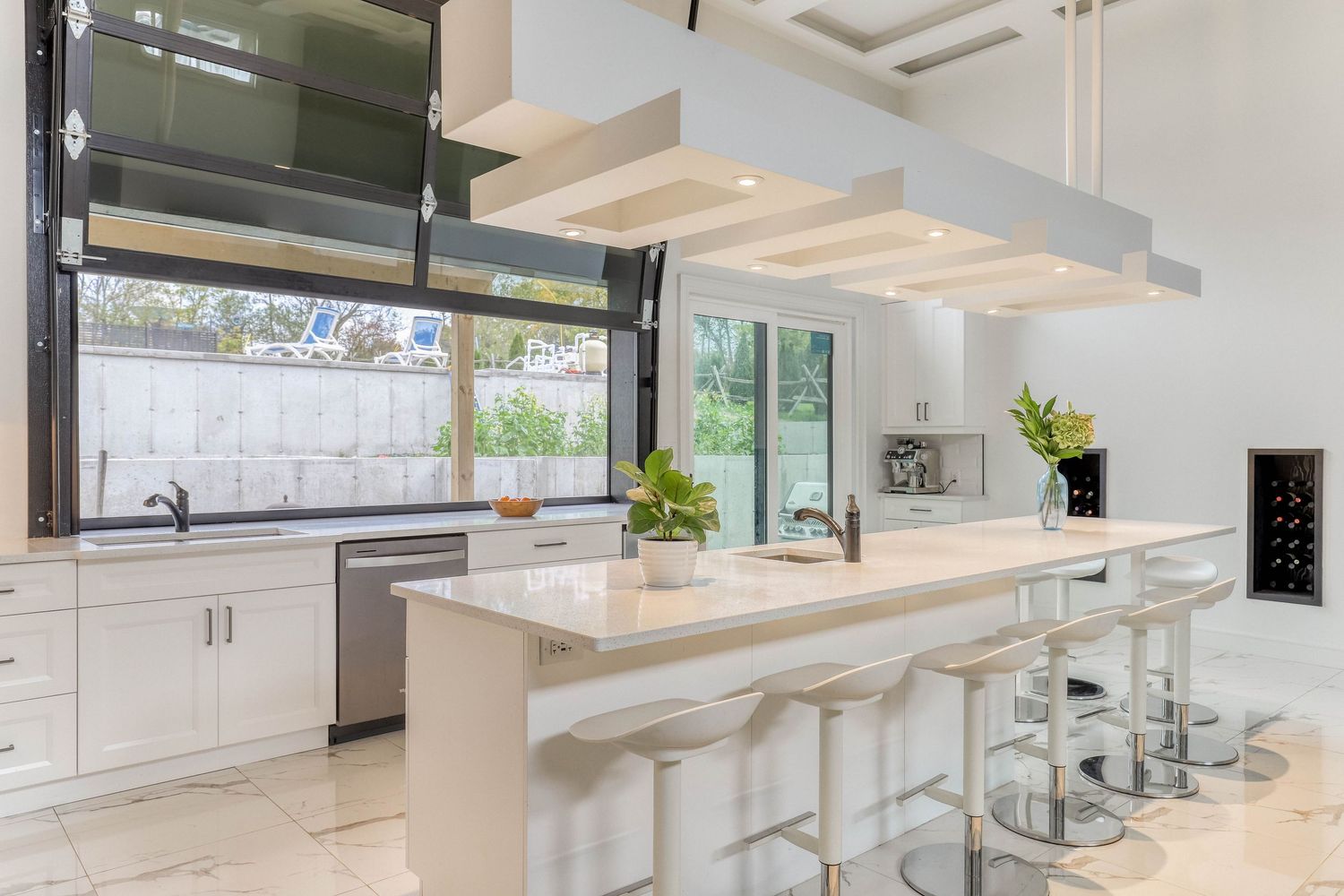 Contemporary white kitchen with suspended wooden ceiling beams and sleek cabinetry.