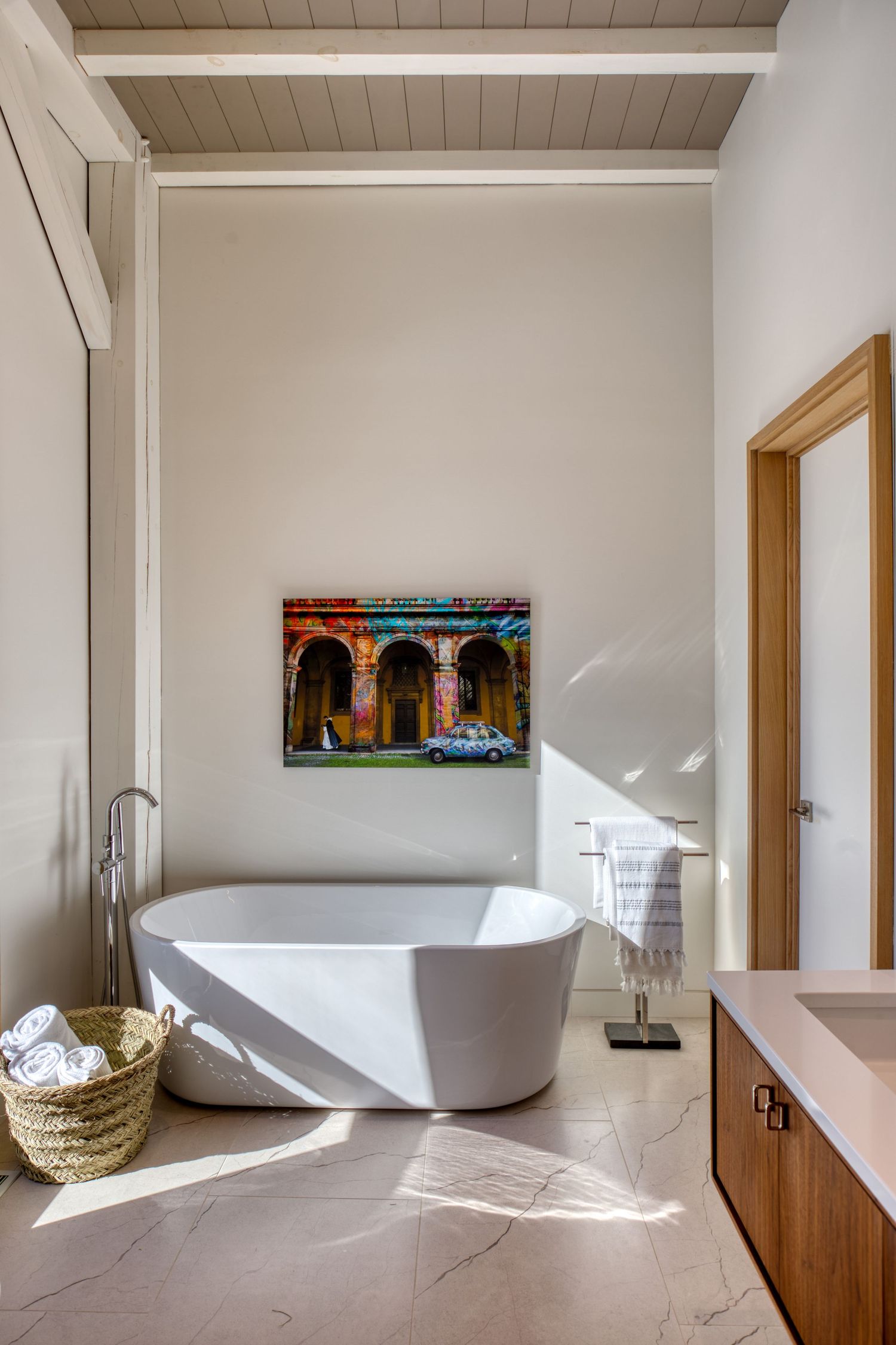 Modern luxury bathroom with freestanding tub and wooden accents in bright natural light.