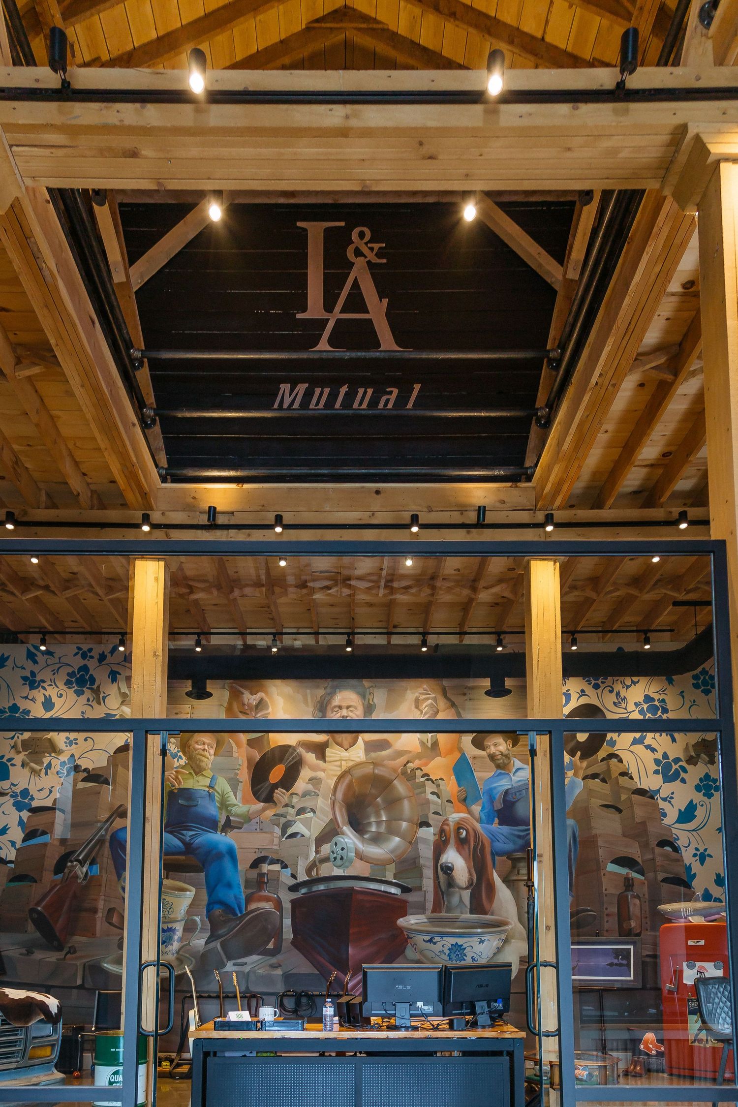 Modern industrial-style interior with wooden beams, pendant lighting and decorative wall murals in a commercial space.