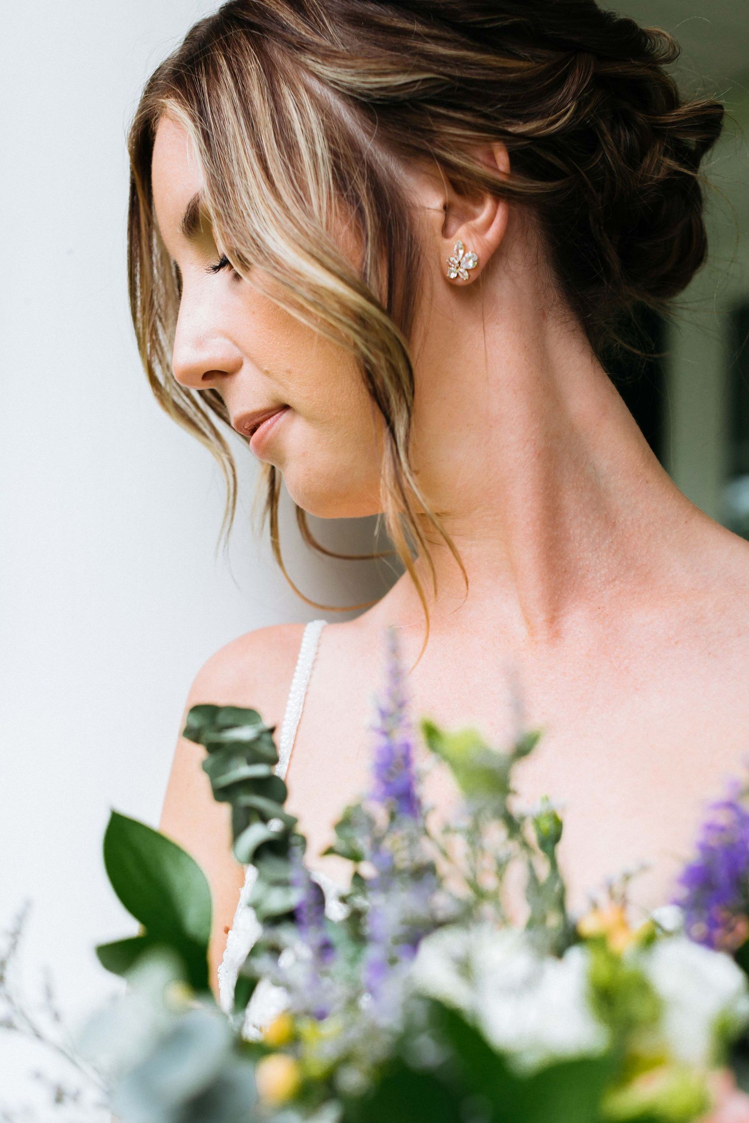 Elegant bridal portrait with soft profile view and colorful bouquet details.