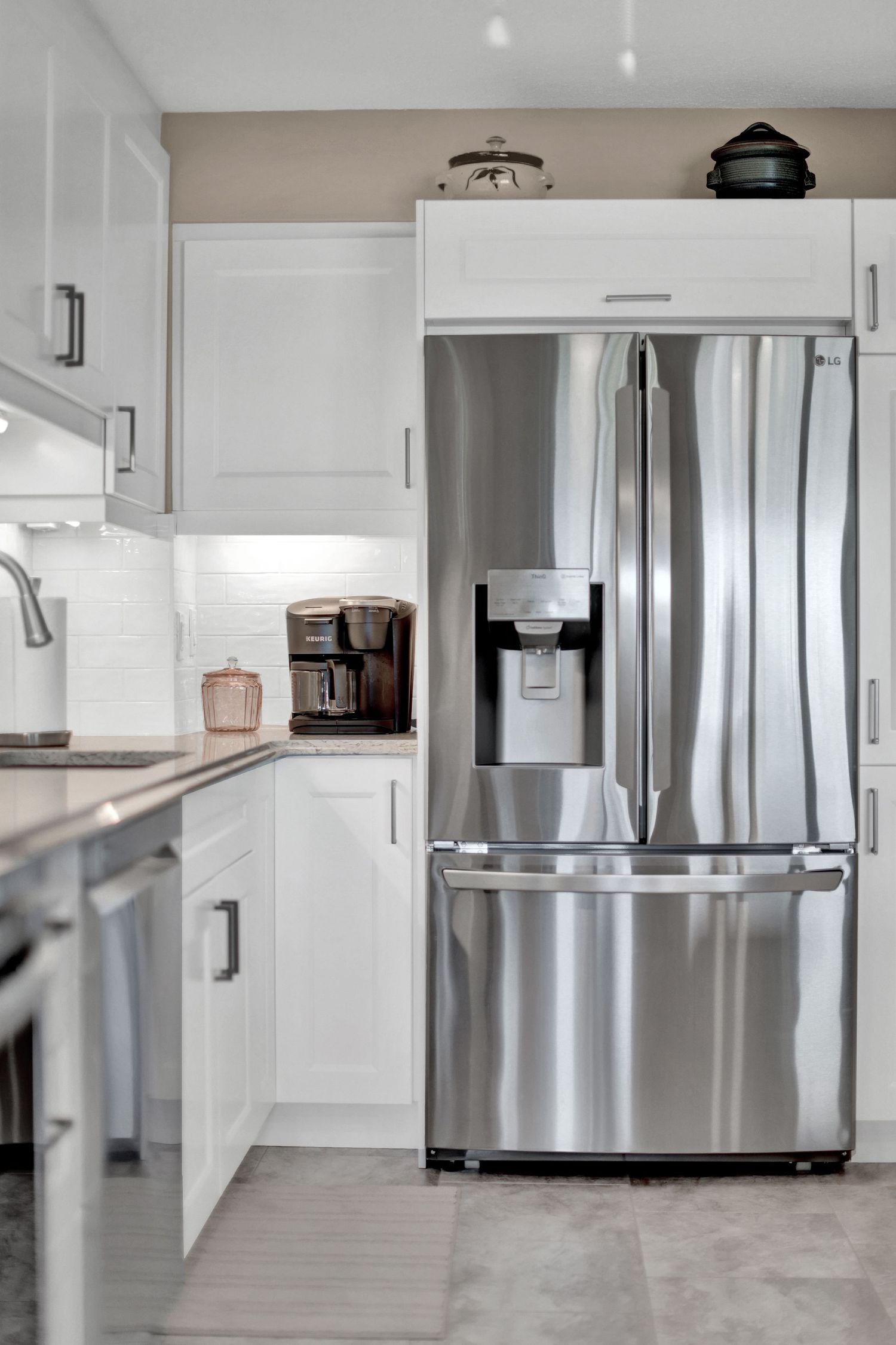 Clean minimalist kitchen design with white cabinets and stainless steel refrigerator.