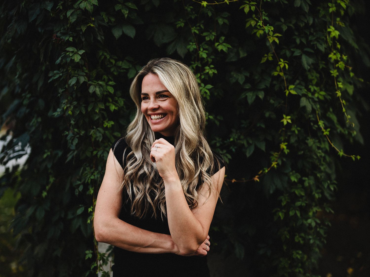 A casual outdoor portrait against a wall of green ivy in natural lighting.