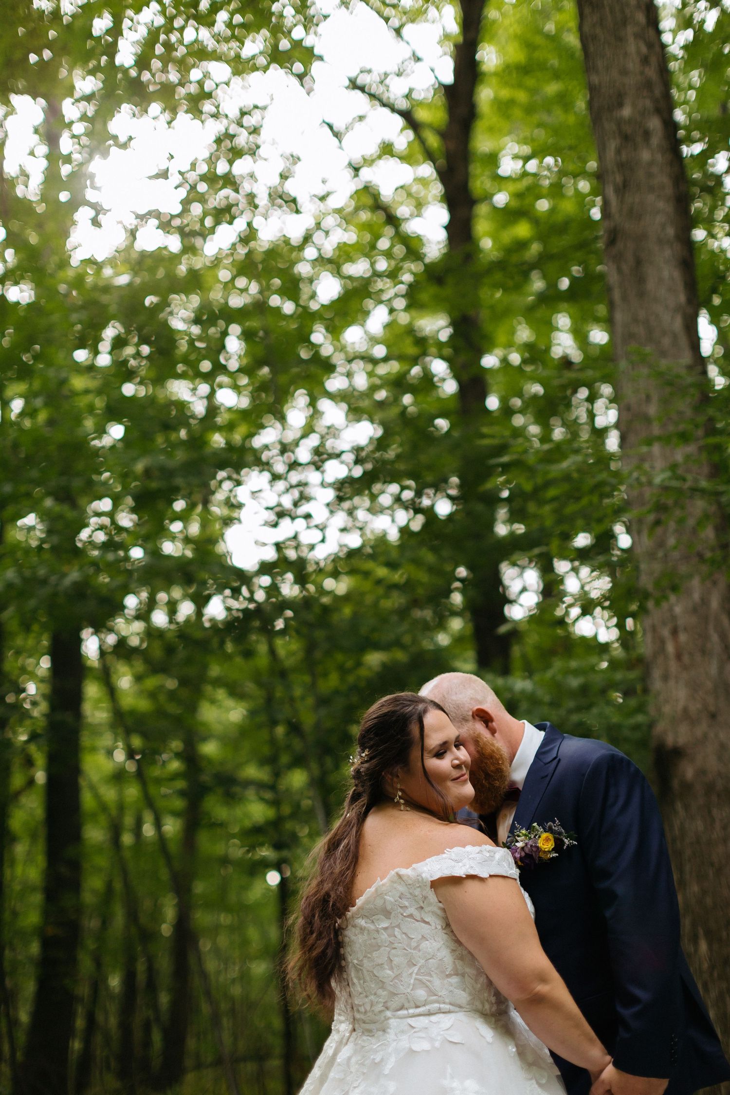 A romantic wedding moment captured in a lush green forest setting.