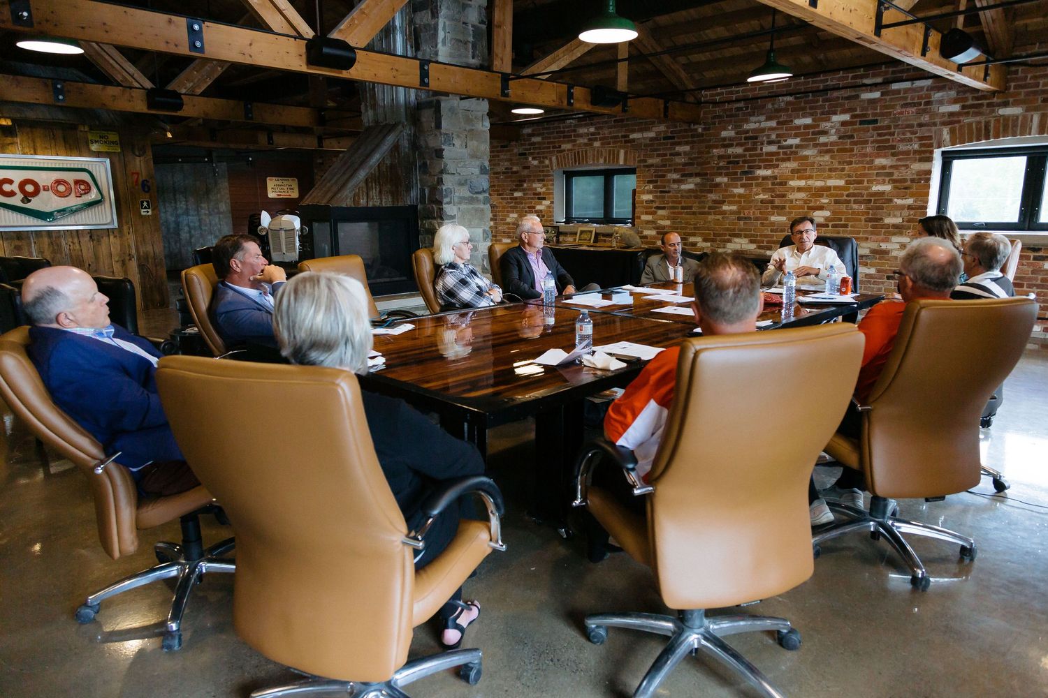 Business meeting in progress at an industrial-style space with exposed brick and leather seating.