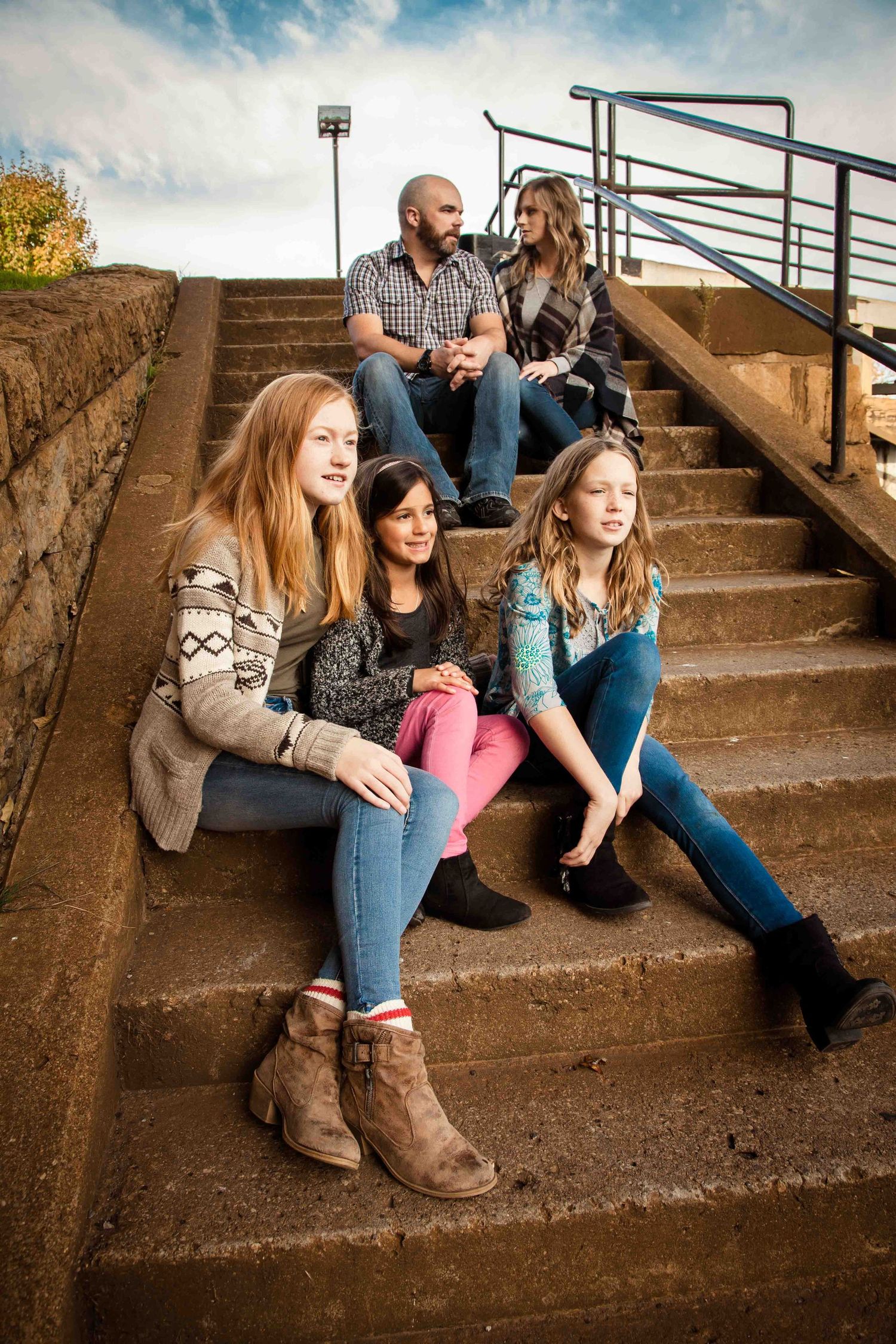 Group sitting on concrete steps during autumn outdoor photography session.
