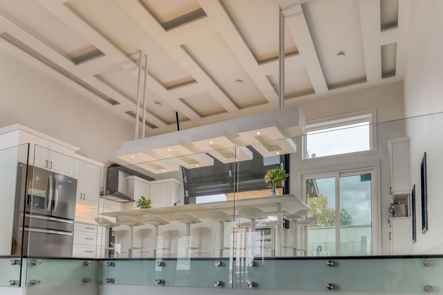 Spacious open concept kitchen with high ceilings and glass panel details.