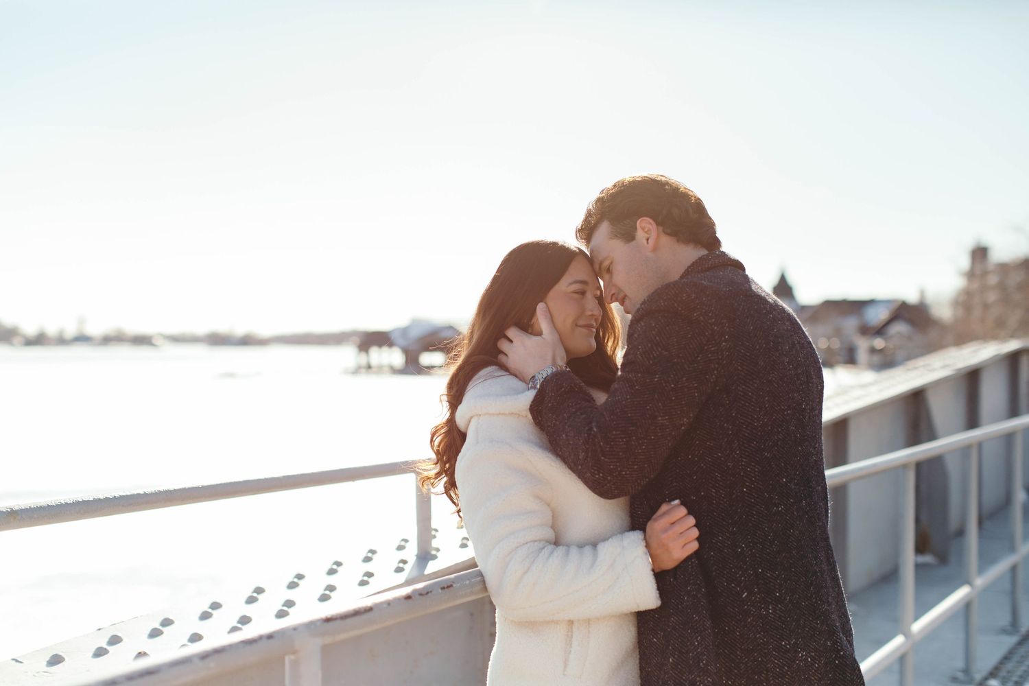A romantic winter scene of a couple embracing on a snowy waterfront.