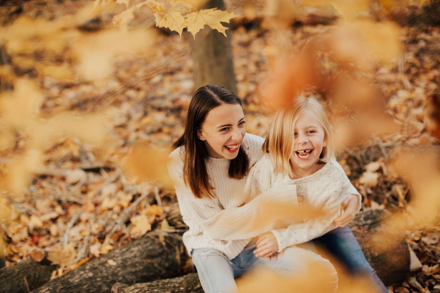 Family playing in golden autumn leaves during outdoor photo session.