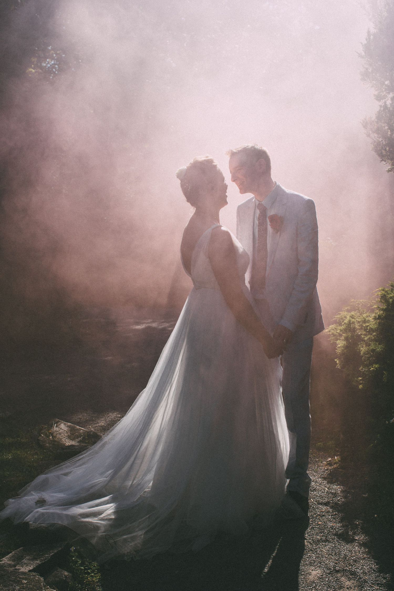 A romantic wedding portrait in misty forest lighting with flowing white dress.