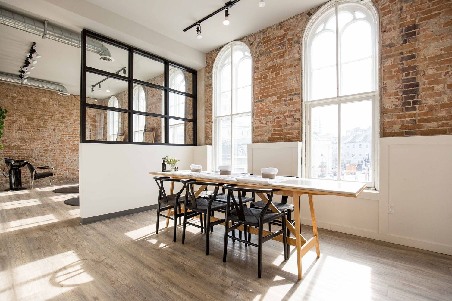 Bright dining area with exposed brick walls, arched windows, and hardwood flooring in an industrial-style space.
