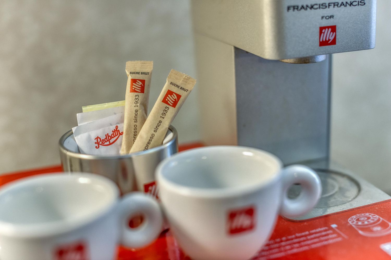 Coffee cups and saucers arranged in a row with red accents.