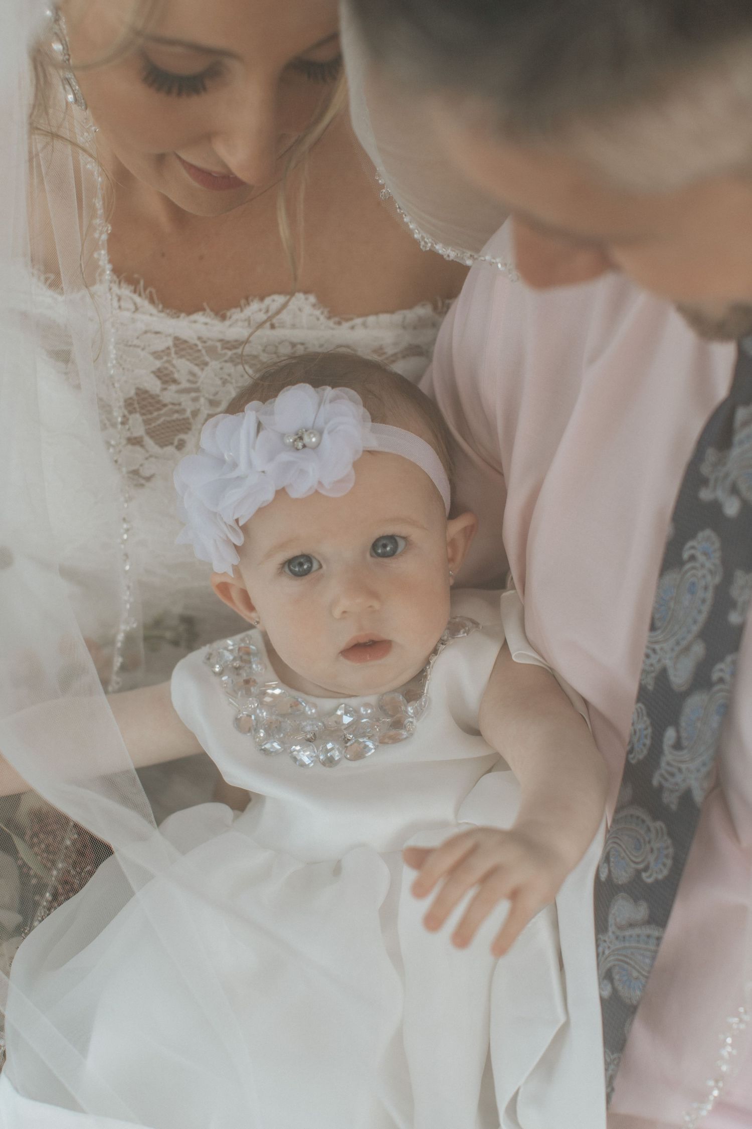 Intimate wedding portrait with baby wearing white dress and crystal accessories.