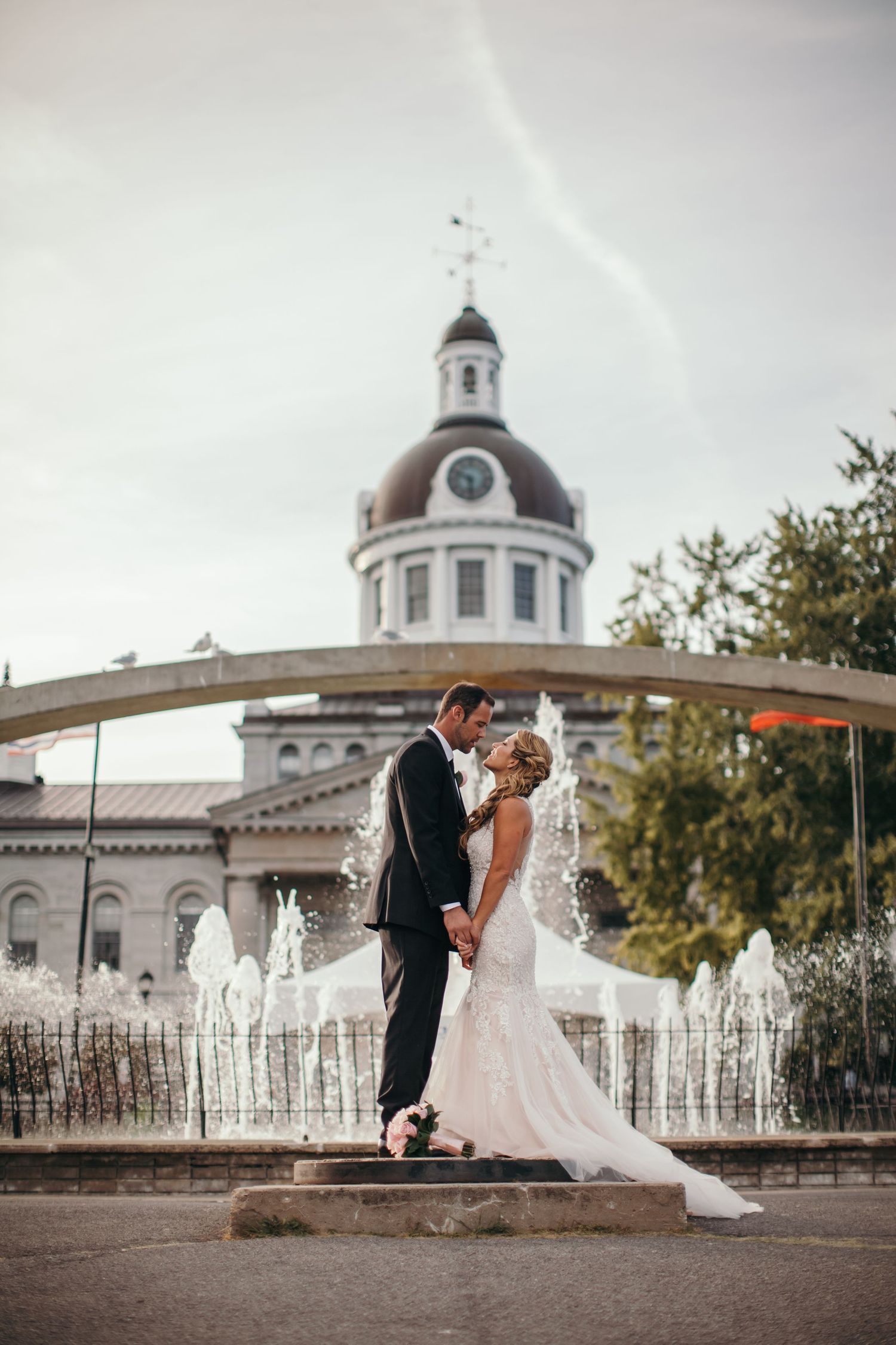 Romantic wedding portrait in front of historic domed building with fountain.
