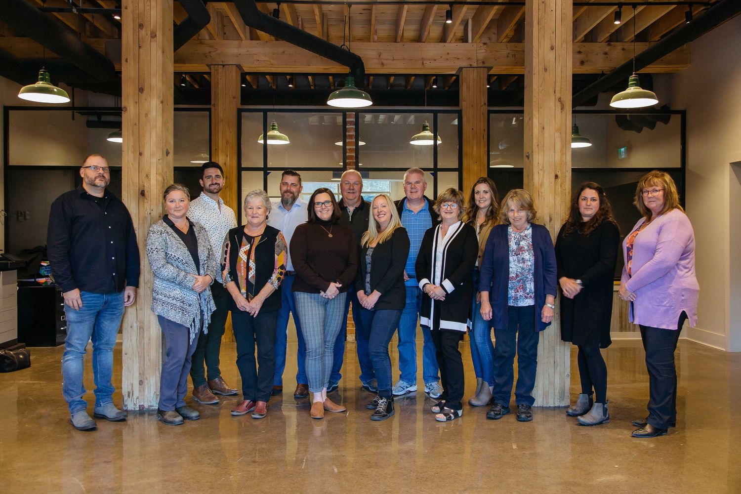 Large group of people lined up against a wooden wall in business casual attire.