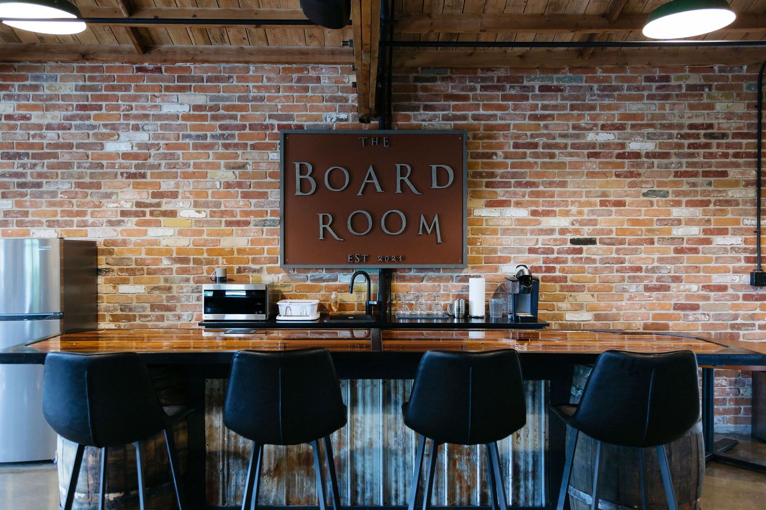 Empty board room with exposed brick walls, modern lighting, and conference seating.