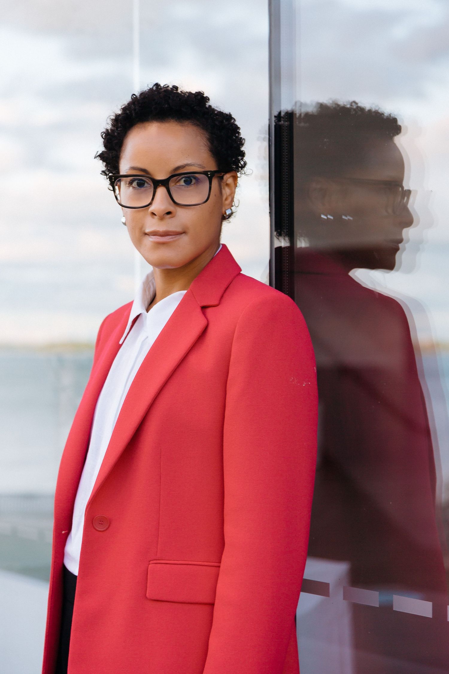 Professional portrait series showing red blazer against reflective window backdrop.
