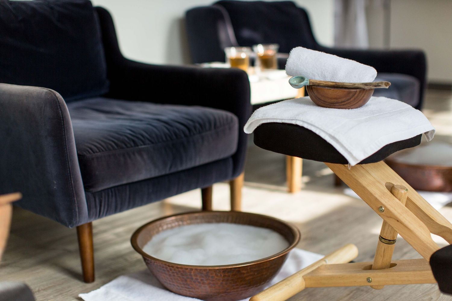 Navy velvet armchair with white throw pillows and wooden side table in a contemporary living space.
