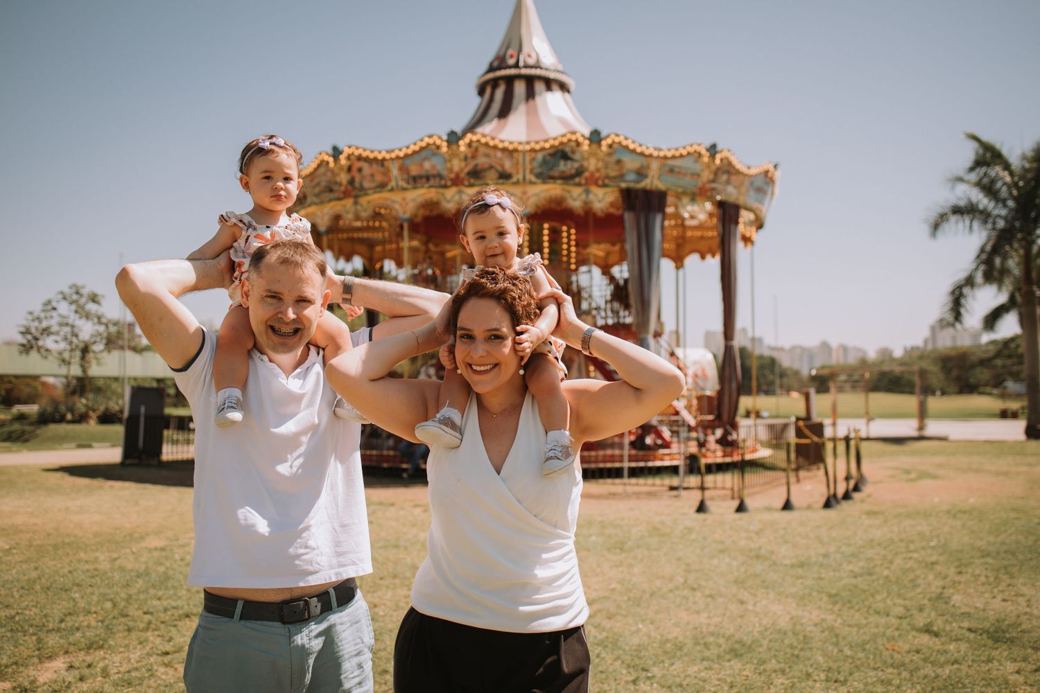 Outdoor family portraits with a decorative carousel visible in the park setting.