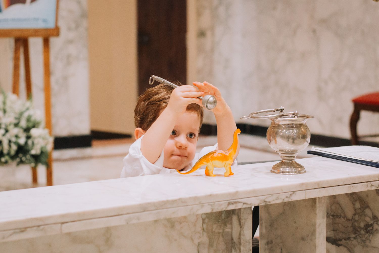 A small child peers over a white marble altar during a church ceremony.