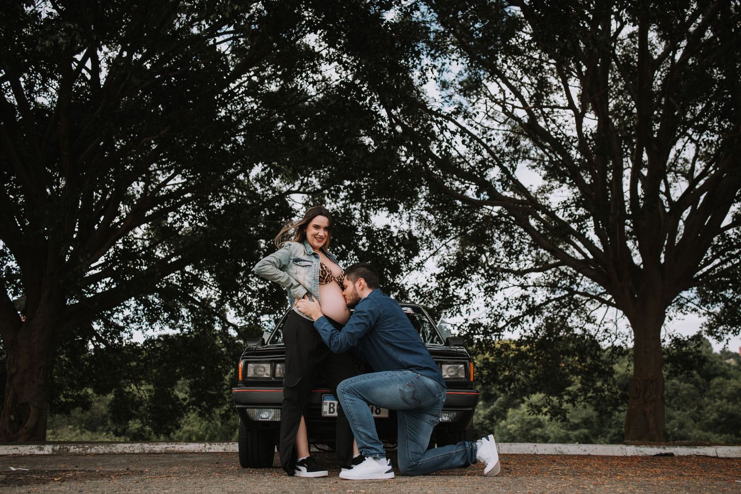 Natural outdoor maternity session under large trees at dusk.