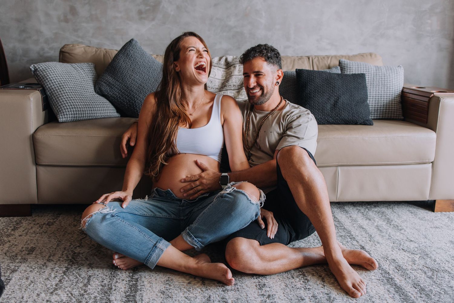 Natural lifestyle maternity photography session on grey carpet in modern living room.