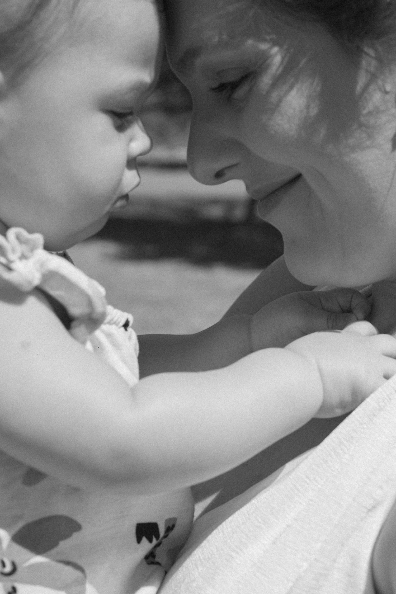 Close-up black and white portrait of two young children sharing a tender moment.