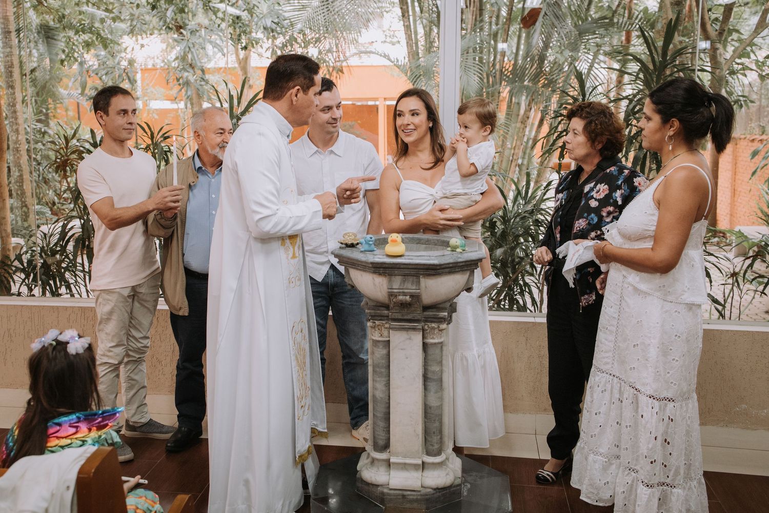 A group gathers for a celebration in a bright indoor space with white decor.