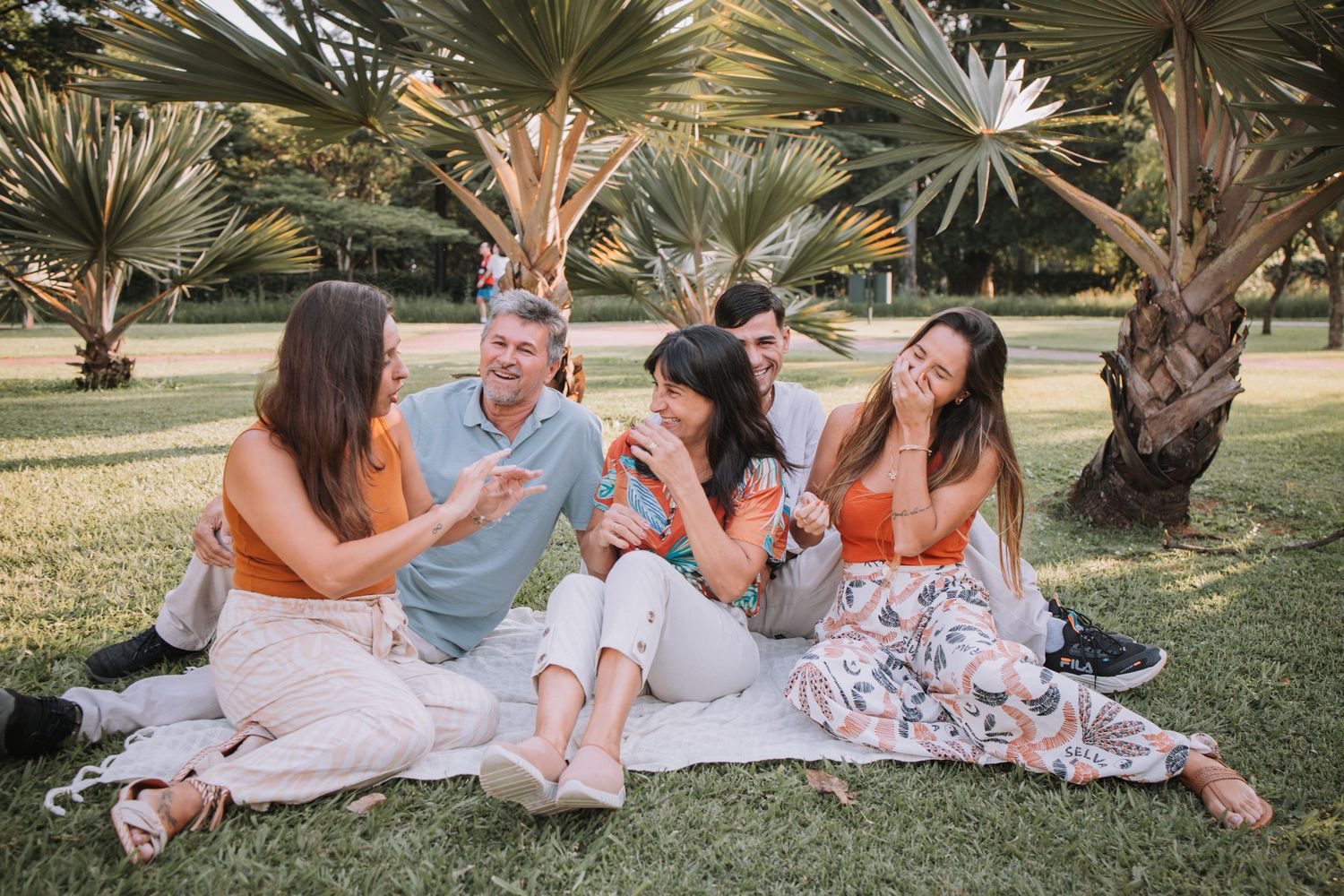 Family members lying on blanket sharing laughs during outdoor photo session.